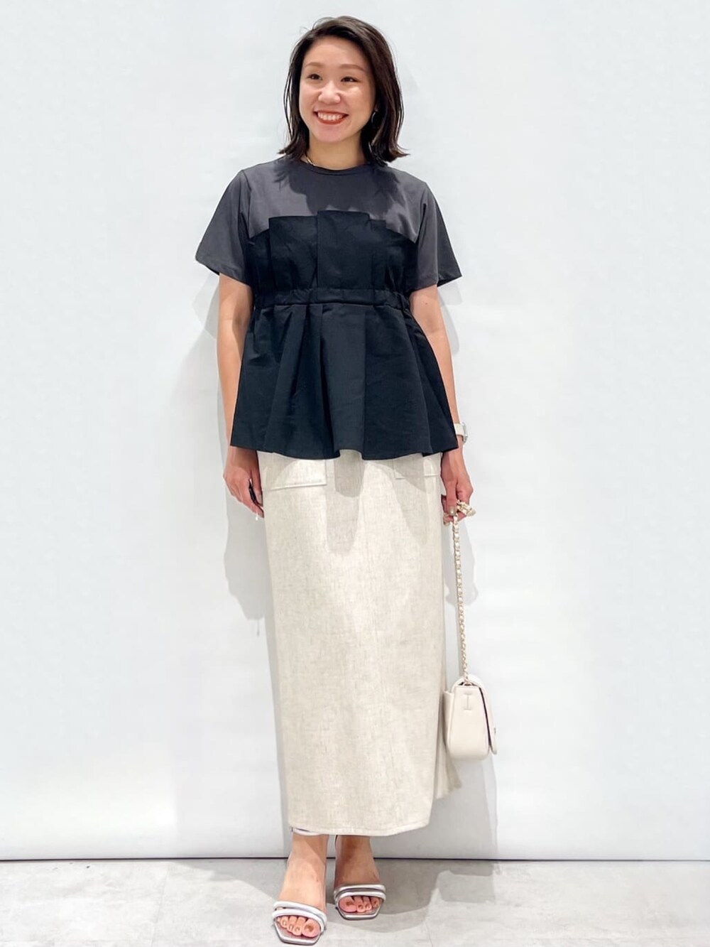 ブラック系のTシャツ/カットソー、ベージュ系のスカート、ホワイト系のショルダーバッグを着用したレディースの夏コーディネートの3枚目の写真