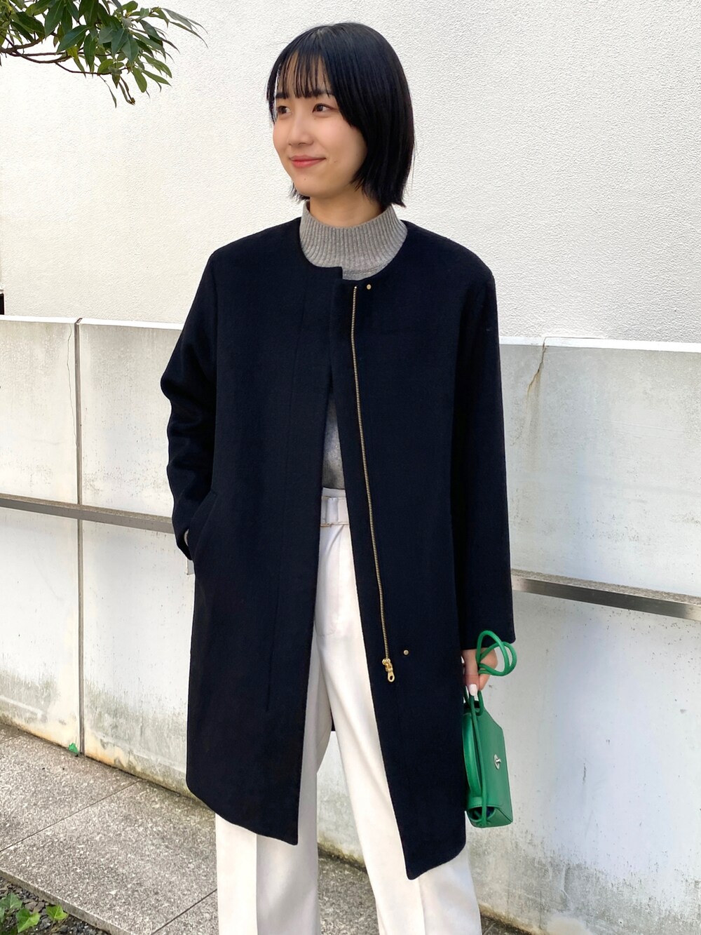 ブラック系のノーカラーコート、グレー系のその他パンツ、グレー系のニット/セーターを着用したレディースの冬コーディネートの2枚目の写真