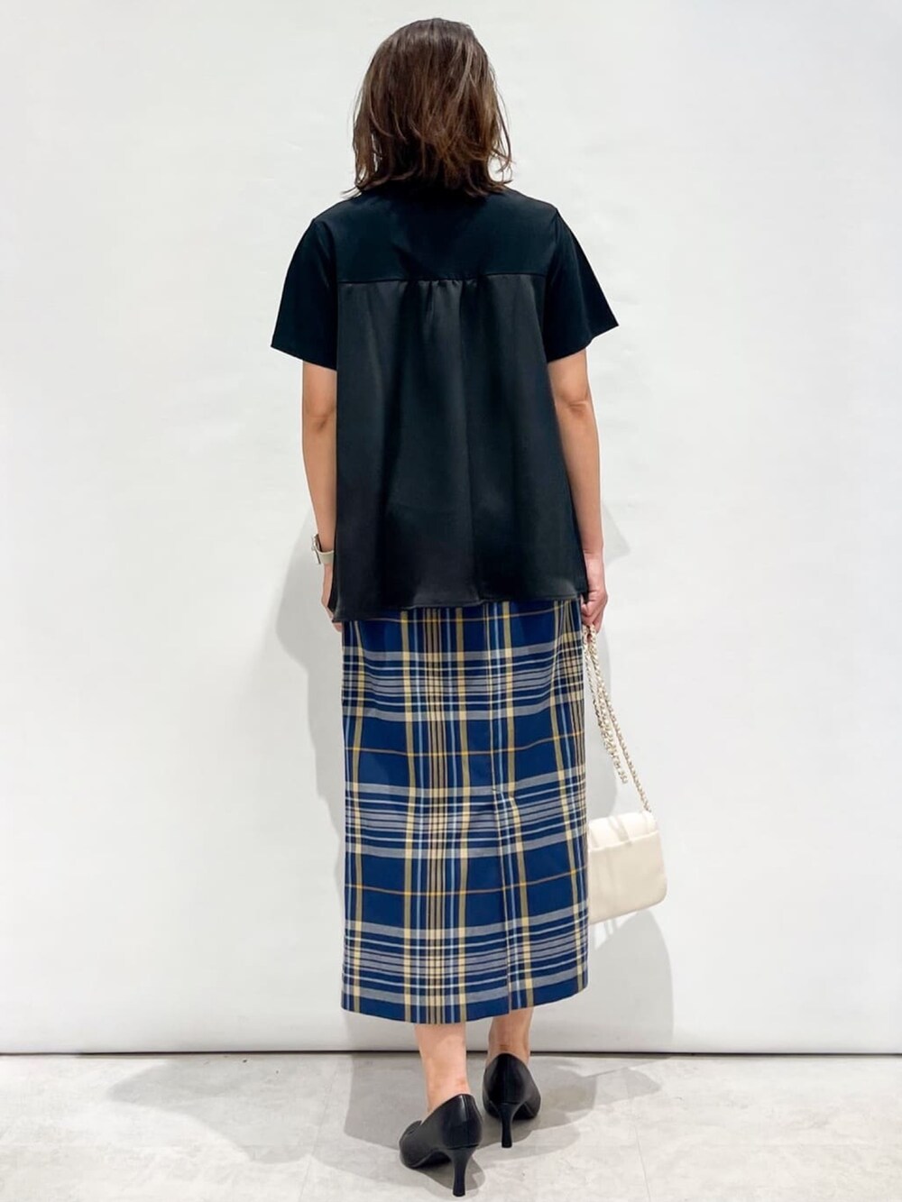ブルー系のスカート、ブラック系のパンプス、ホワイト系のショルダーバッグを着用したレディースの夏コーディネートの6枚目の写真