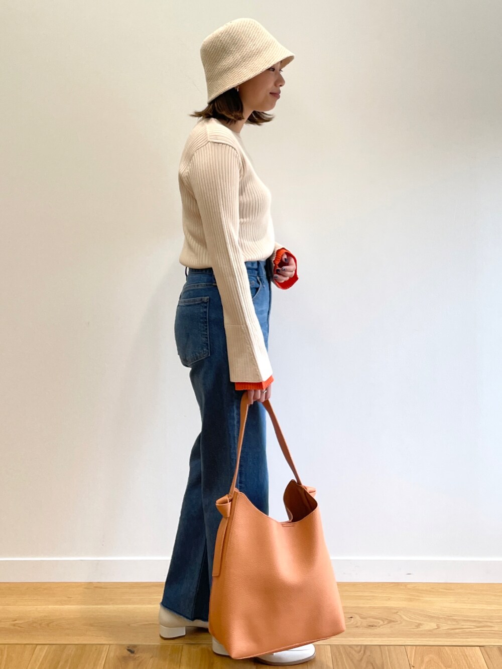 ベージュ系のニット/セーター、ブルー系のデニムパンツ、ホワイト系のその他シューズを着用したレディースの冬コーディネートの2枚目の写真