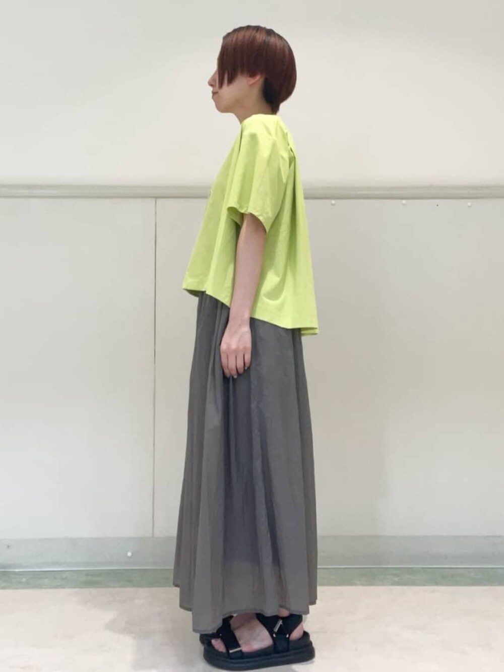 グレー系のスカート、ブラック系のサンダル、グリーン系のTシャツ/カットソーを着用したレディースの春コーディネートの3枚目の写真