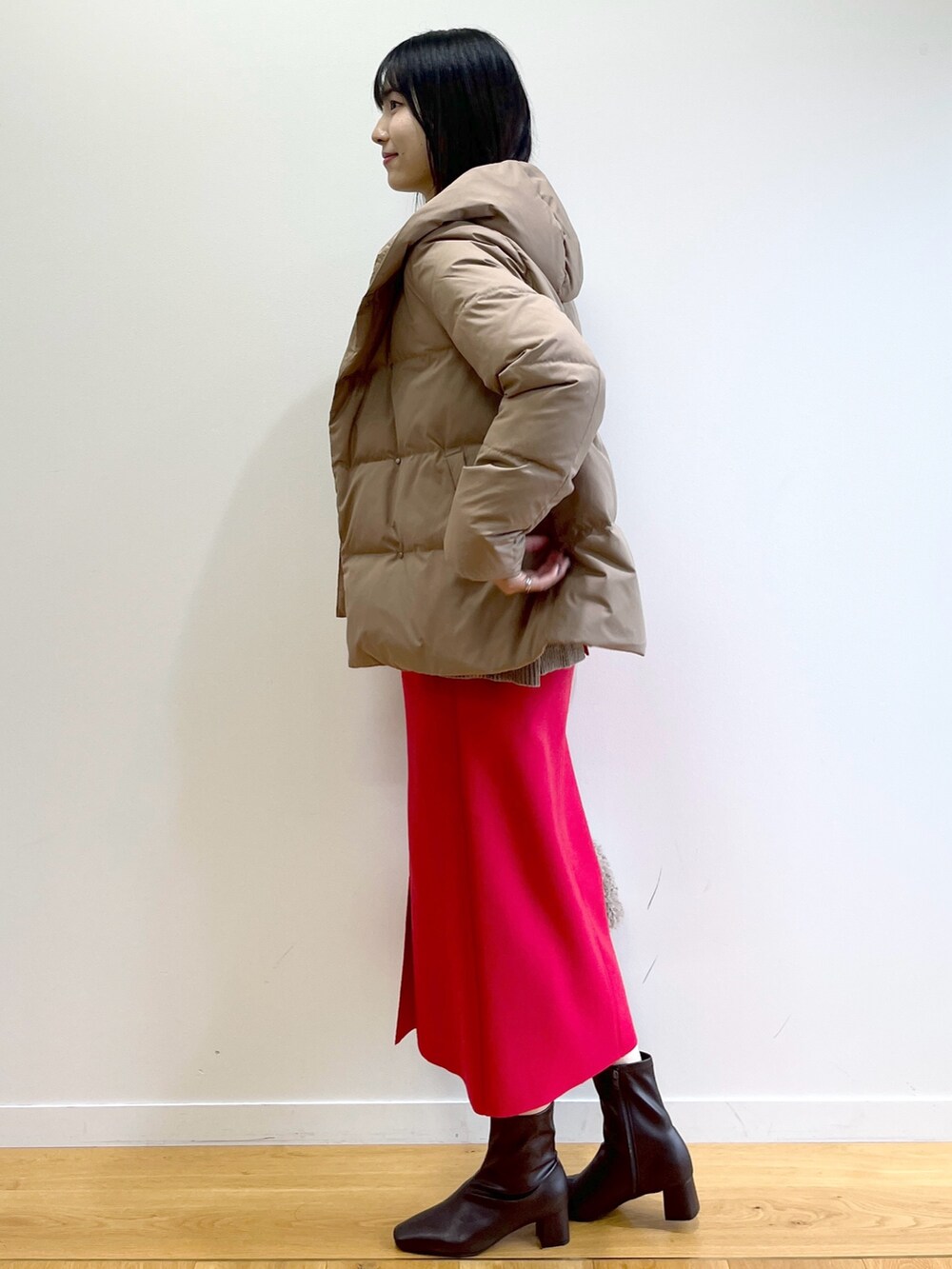 イエロー系のダウンジャケット/コート、ベージュ系のニット/セーター、レッド系のスカートを着用したレディースの秋コーディネートの3枚目の写真