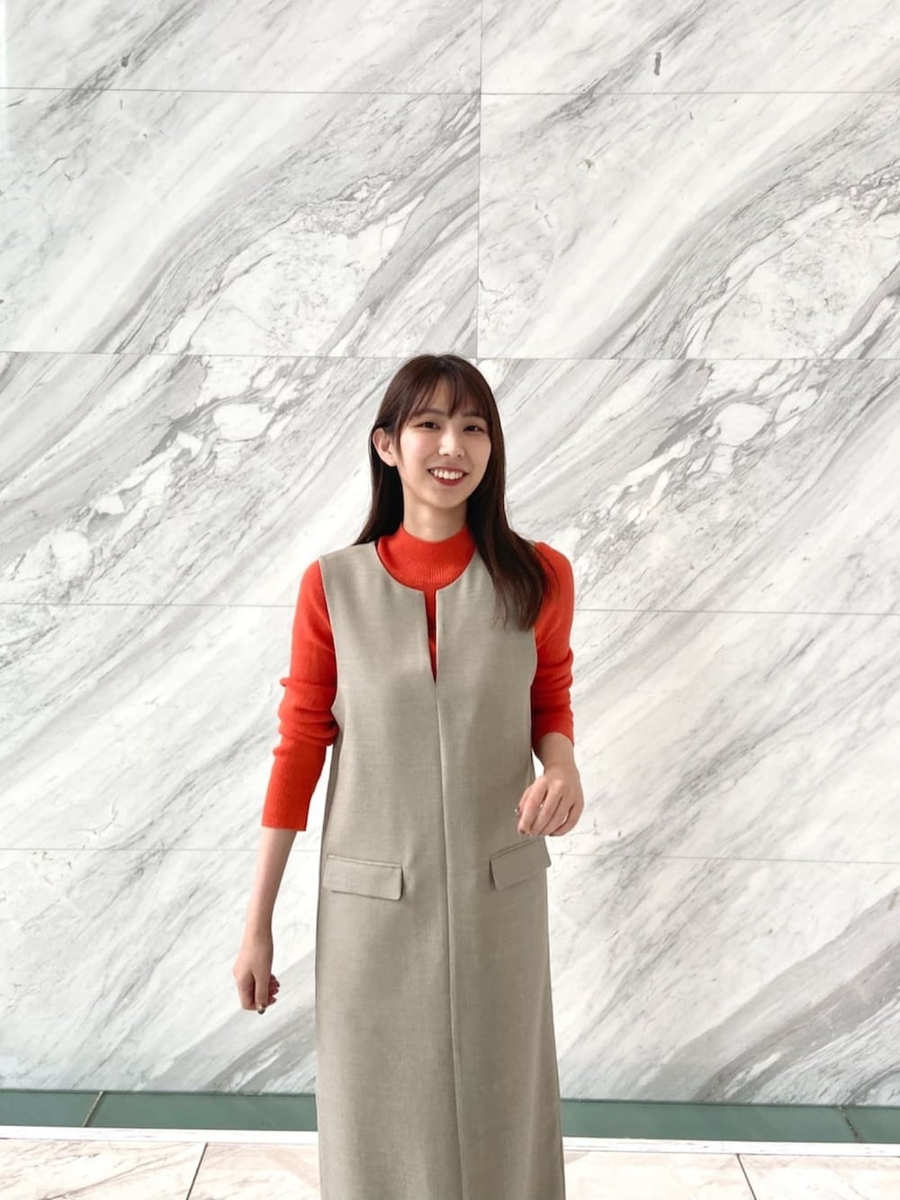 オレンジ系のニット/セーター、ベージュ系のワンピース、ホワイト系のブーツを着用したレディースの秋コーディネートの6枚目の写真