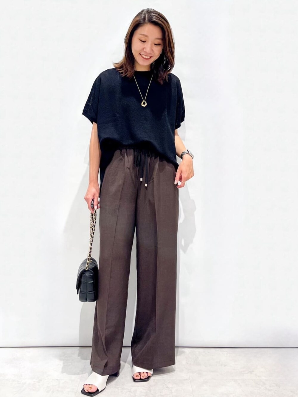 ブラウン系のその他パンツ、ホワイト系のサンダル、ブラック系のショルダーバッグを着用したレディースの夏コーディネートの2枚目の写真