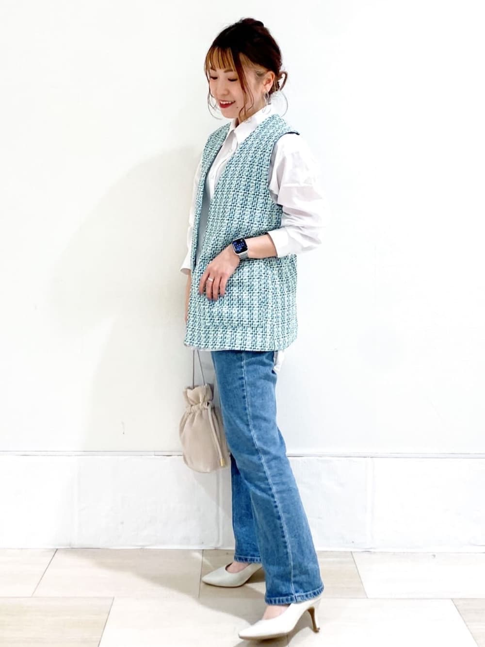 ホワイト系のシャツ/ブラウス、ブルー系のベスト、ベージュ系のショルダーバッグを着用したレディースの春コーディネートの2枚目の写真