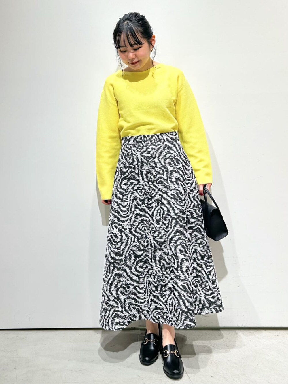 イエロー系のニット/セーター、ブルー系のテーラードジャケット、ブラック系のスカートを着用したレディースの冬コーディネートの3枚目の写真