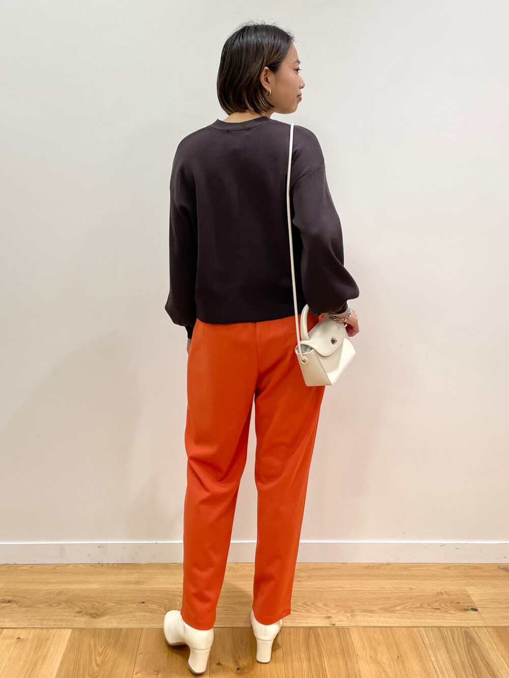 ブラウン系のカーディガン/ボレロ、オレンジ系のその他パンツ、ホワイト系のショルダーバッグを着用したレディースの秋コーディネートの2枚目の写真