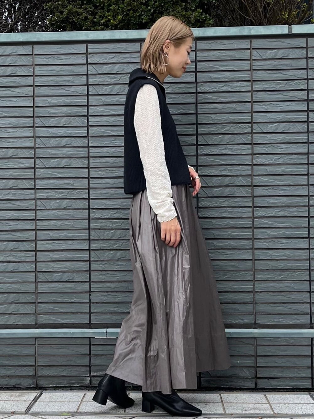 ブラック系のニット/セーター、ホワイト系のTシャツ/カットソー、グリーン系のスカートを着用したレディースの秋コーディネートの3枚目の写真