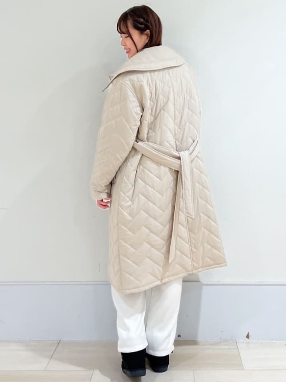 ベージュ系のステンカラーコート、ブルー系のニット/セーター、ホワイト系のその他パンツを着用したレディースの冬コーディネートの3枚目の写真