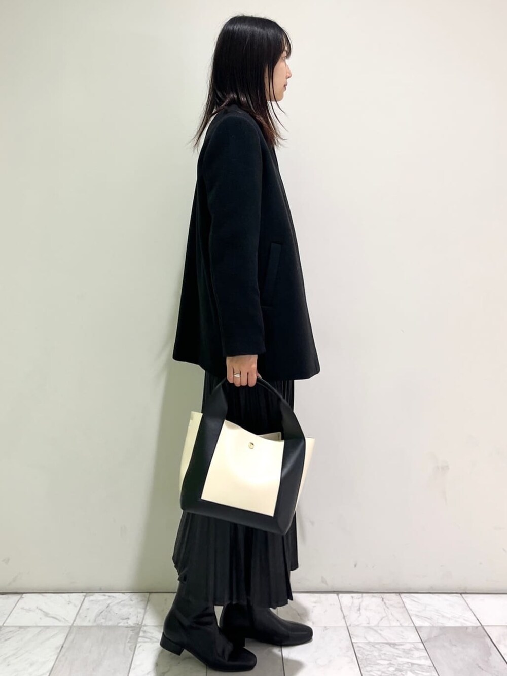 ブラック系のブーツ、ブラック系のTシャツ/カットソー、ブラック系のノーカラーコートを着用したレディースの秋コーディネートの2枚目の写真