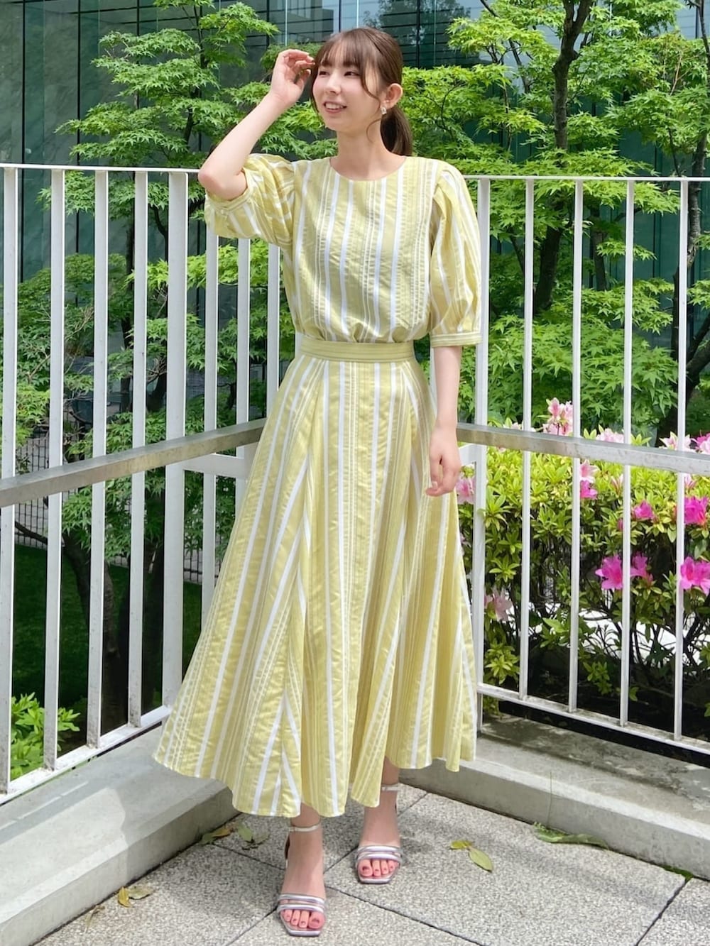 イエロー系のシャツ/ブラウス、イエロー系のスカート、シルバー系のサンダルを着用したレディースの春コーディネートの2枚目の写真