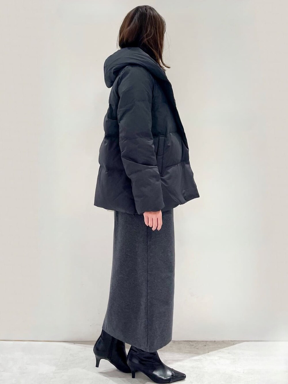 ブラック系のダウンジャケット/コート、グレー系のスカート、ブラック系のブーツを着用したレディースの秋コーディネートの3枚目の写真