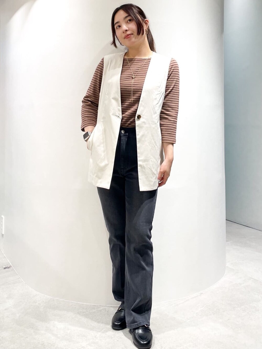 ブラック系のドレスシューズ、ブラック系のデニムパンツ、ホワイト系のベストを着用したレディースの夏コーディネートの4枚目の写真