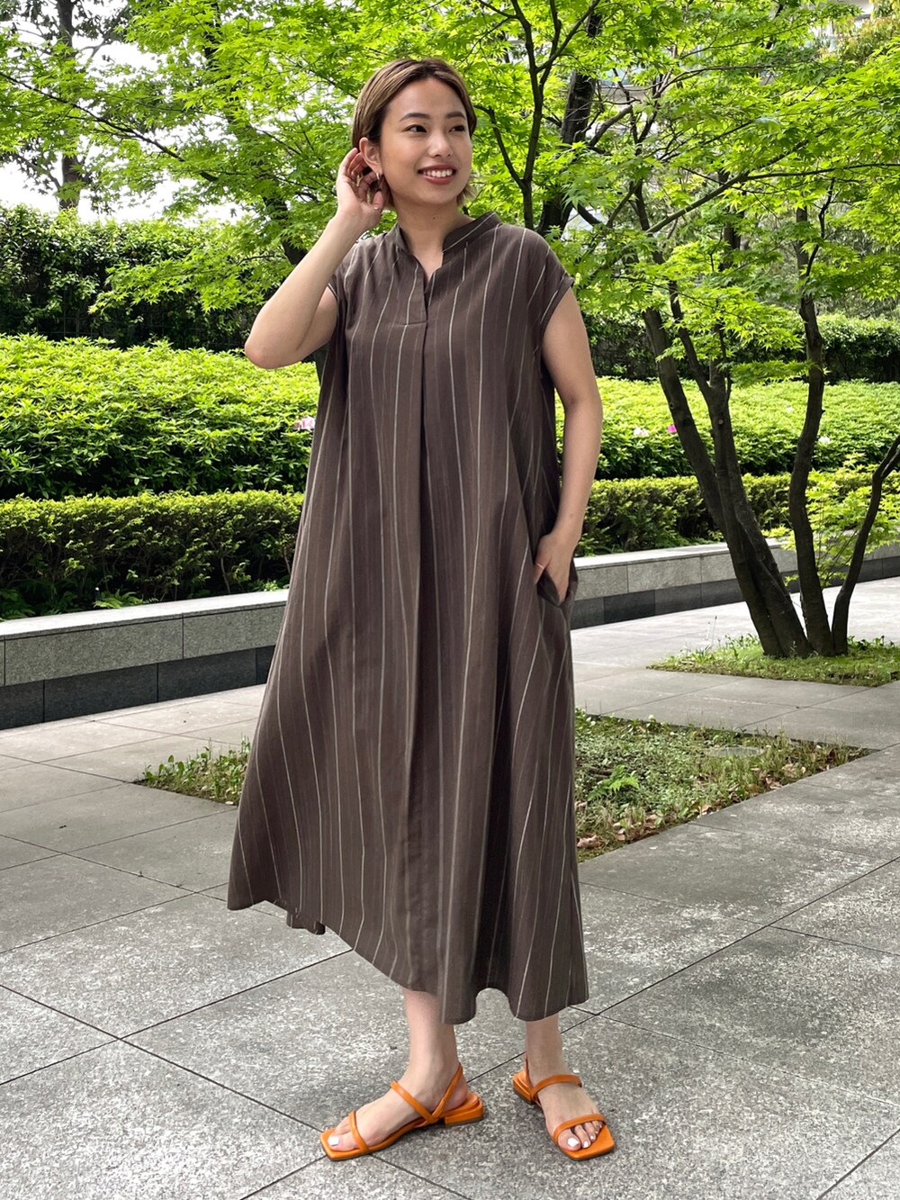 ブラウン系のワンピース、オレンジ系のサンダルを着用したレディースの春コーディネートの2枚目の写真