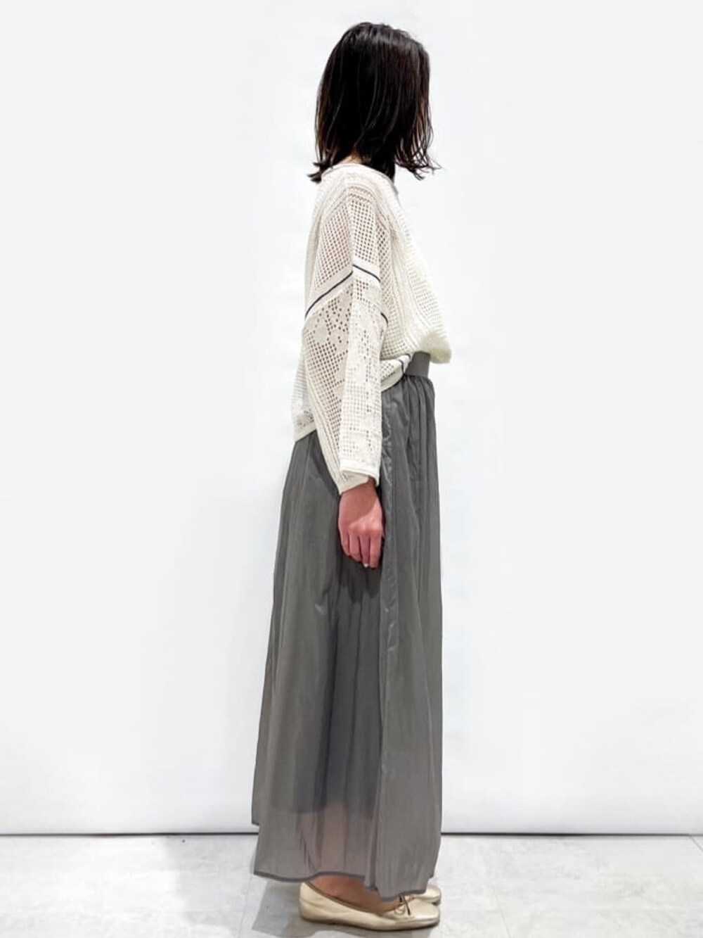 ホワイト系のニット/セーター、グレー系のスカート、ホワイト系のハンドバッグを着用したレディースの春コーディネートの5枚目の写真