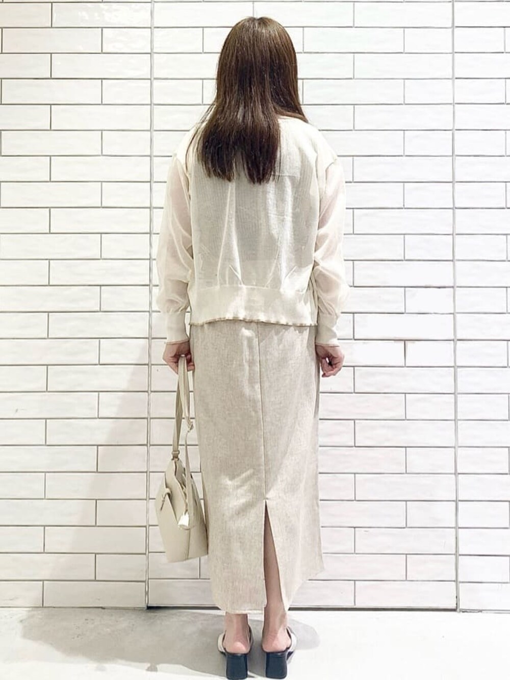ホワイト系のカーディガン/ボレロ、ベージュ系のニット/セーター、ホワイト系のサンダルを着用したレディースの夏コーディネートの3枚目の写真