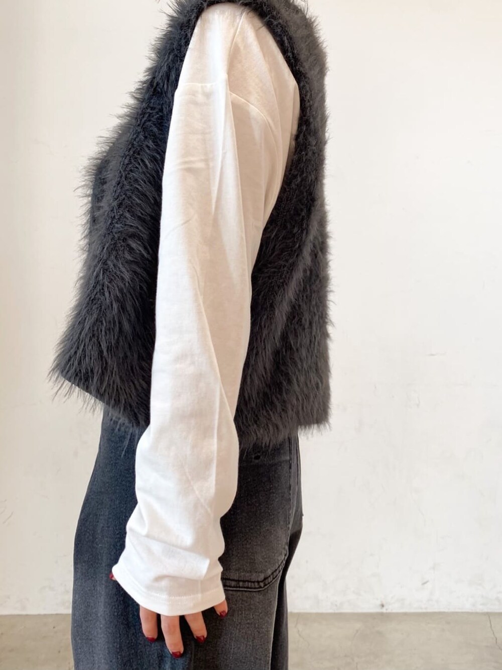 ホワイト系のTシャツ/カットソー、グレー系のベスト、ブラック系のデニムパンツを着用したレディースの秋コーディネートの5枚目の写真