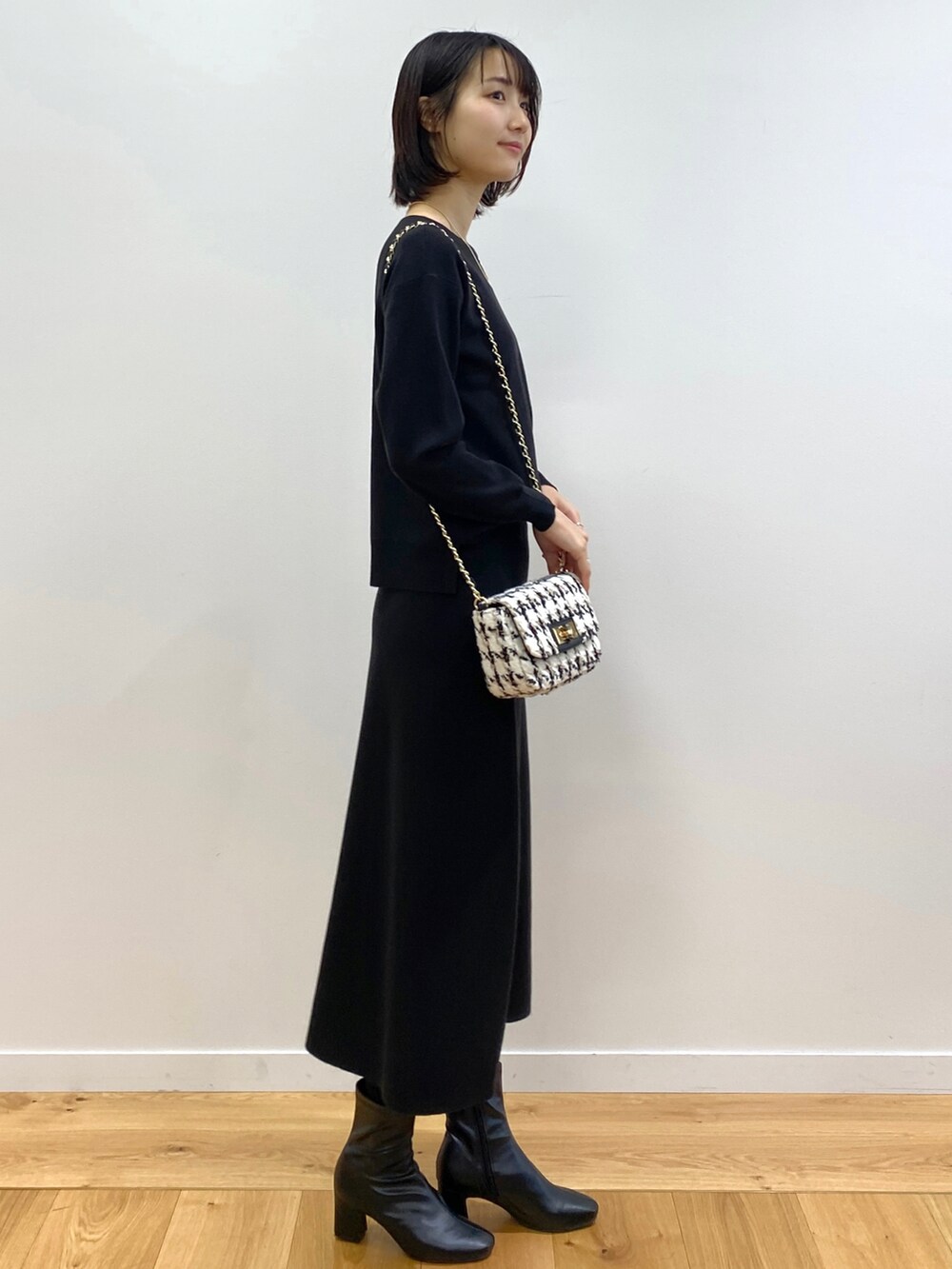 ブラック系のニット/セーター、ブラック系のスカート、ブルー系のノーカラーコートを着用したレディースの冬コーディネートの4枚目の写真