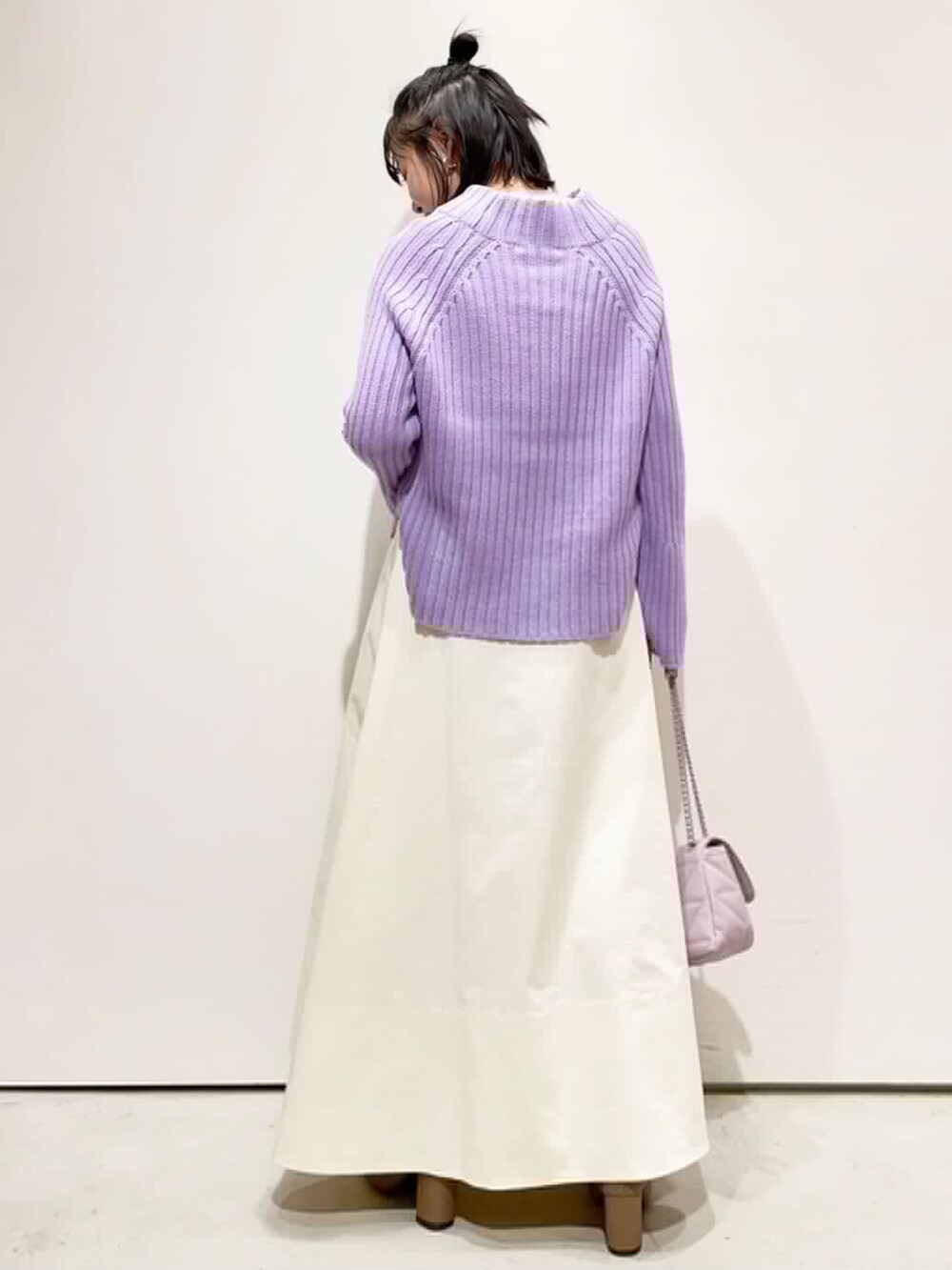 ホワイト系のスカート、パープル系のニット/セーター、ブラウン系のブーツを着用したレディースの冬コーディネートの2枚目の写真