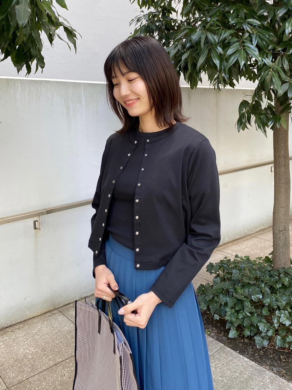 ブルー系のスカート、ブラウン系のサンダル、ブラック系のトートバッグを着用したレディースの春コーディネートの5枚目の写真