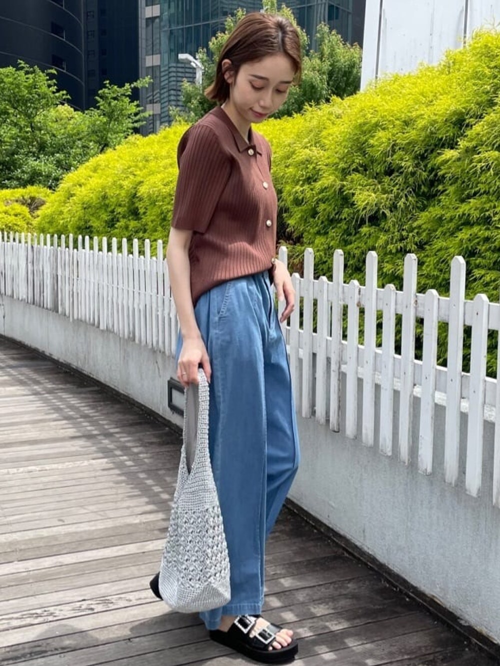 ブラウン系のニット/セーター、ブルー系のデニムパンツ、シルバー系のトートバッグを着用したレディースの春コーディネートの4枚目の写真