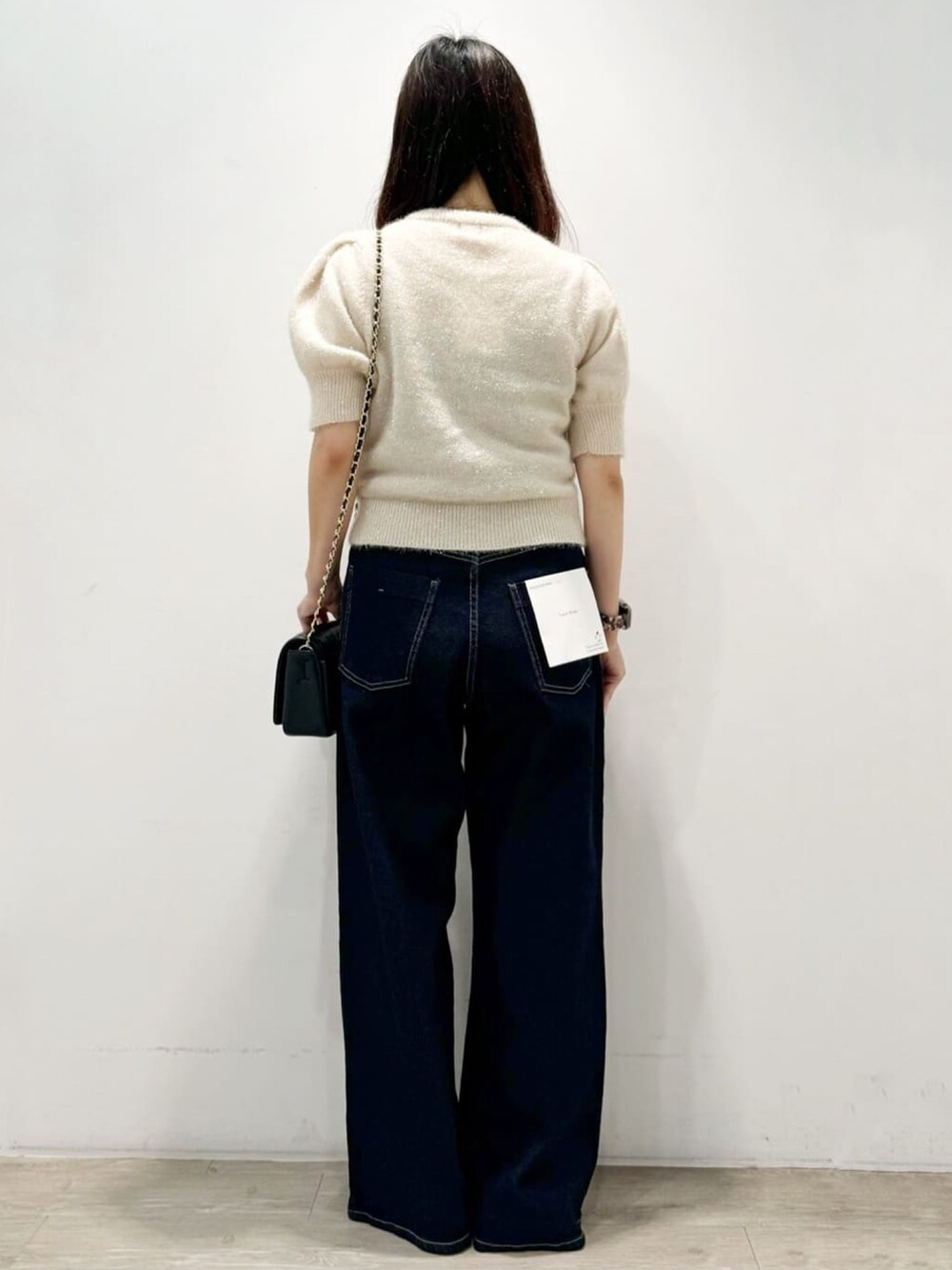 ベージュ系のニット/セーター、ブラック系のショルダーバッグ、ブルー系のデニムパンツを着用したレディースの秋コーディネートの7枚目の写真