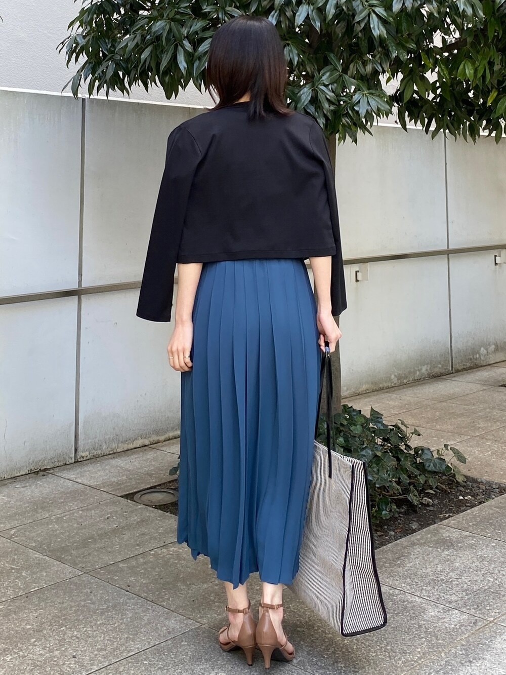 ブルー系のスカート、ブラウン系のサンダル、ブラック系のトートバッグを着用したレディースの春コーディネートの3枚目の写真