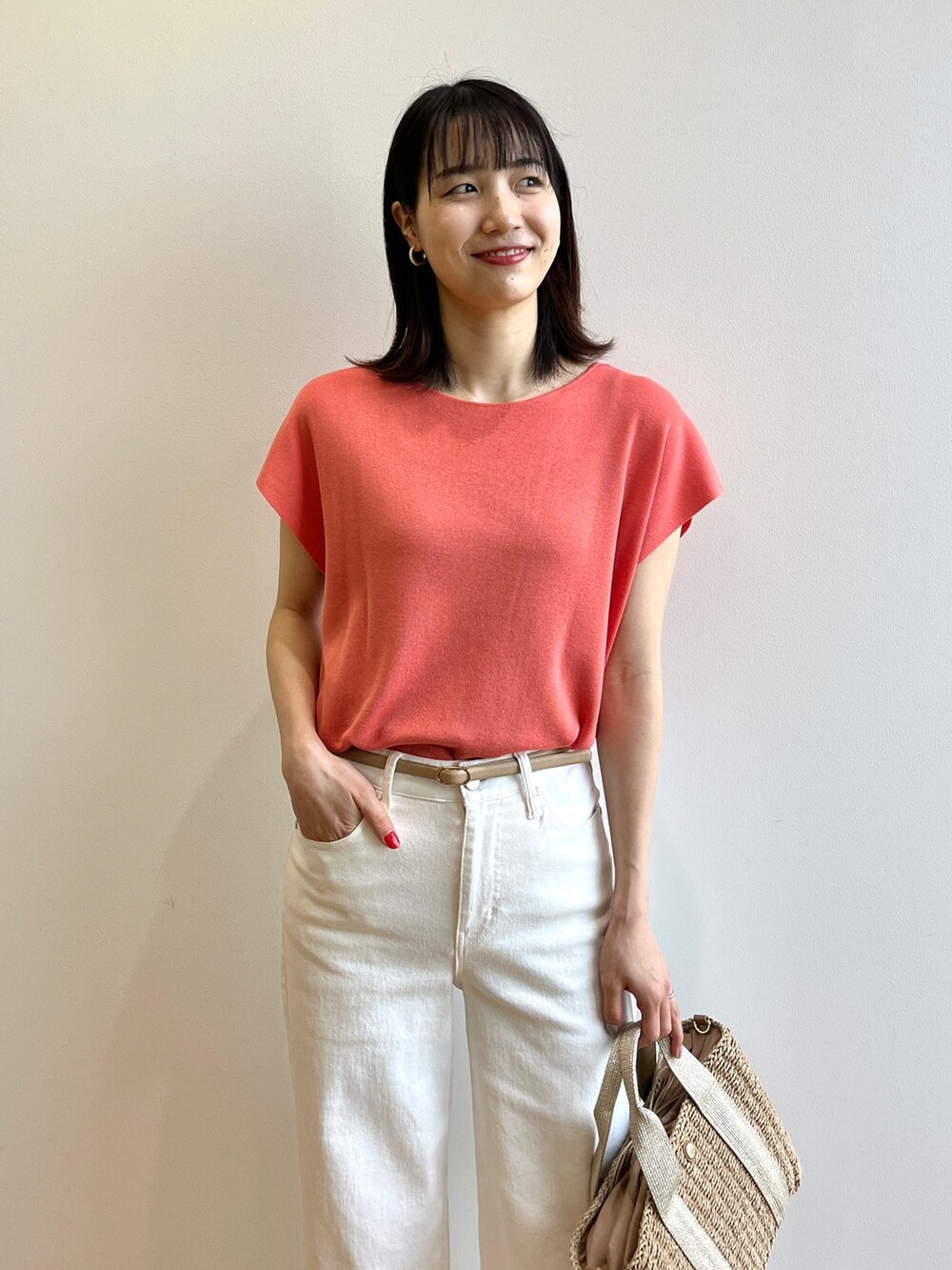 オレンジ系のニット/セーター、ホワイト系のデニムパンツ、ベージュ系のトートバッグを着用したレディースの春コーディネートの4枚目の写真