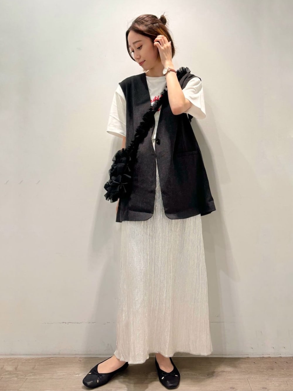 シルバー系のスカート、グレー系のベスト、ホワイト系のTシャツ/カットソーを着用したレディースの夏コーディネートの2枚目の写真