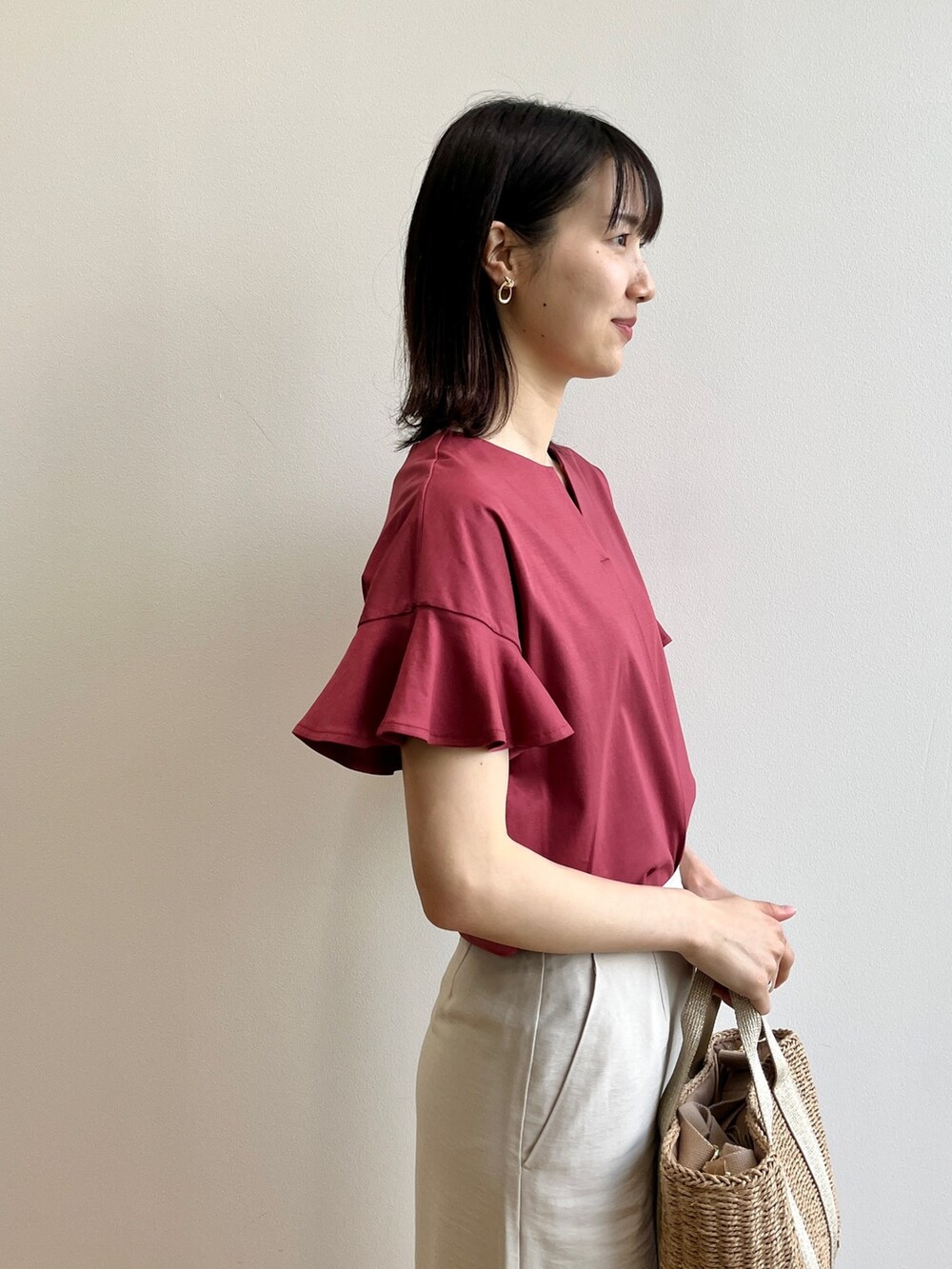 レッド系のTシャツ/カットソー、ゴールド系のサンダル、ベージュ系のスカートを着用したレディースの春コーディネートの5枚目の写真