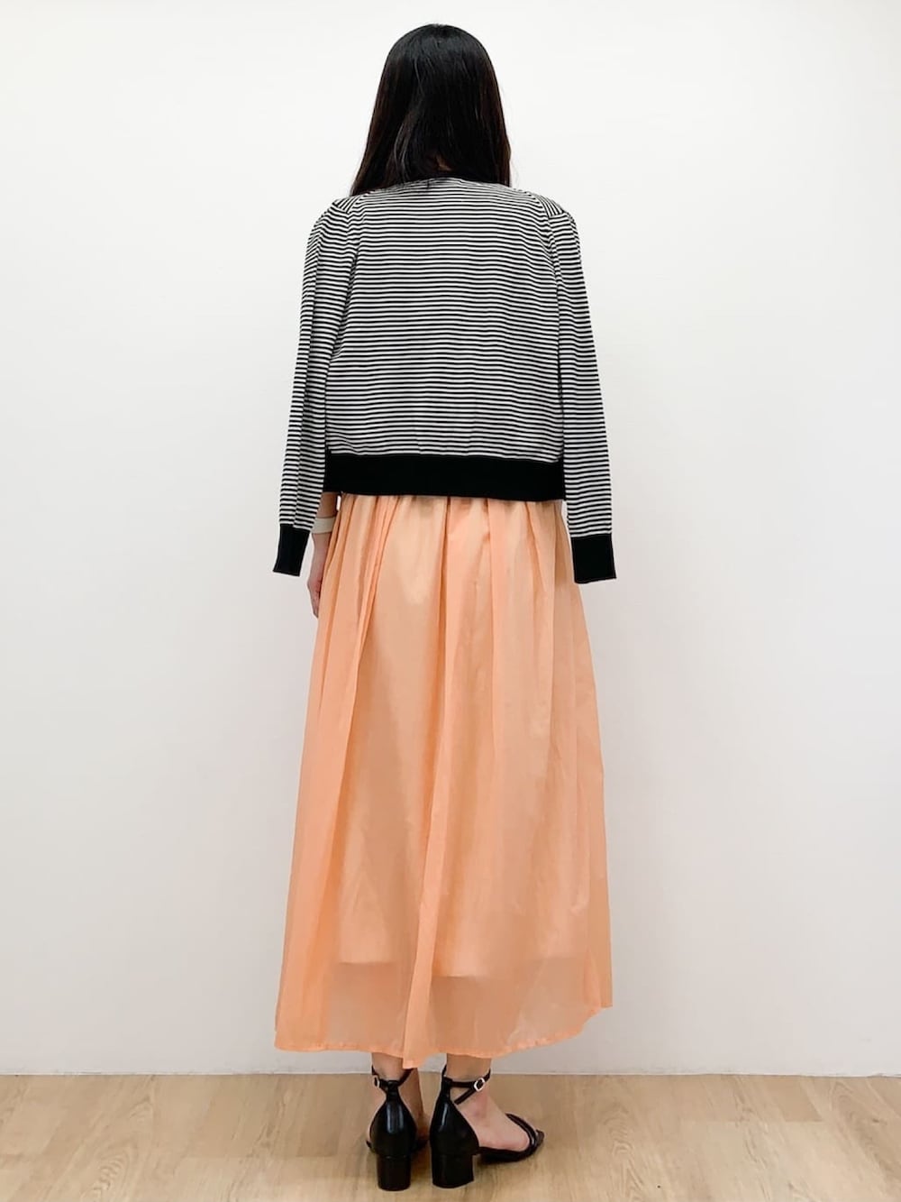 ホワイト系のカーディガン/ボレロ、ホワイト系のTシャツ/カットソー、オレンジ系のスカートを着用したレディースの春コーディネートの3枚目の写真