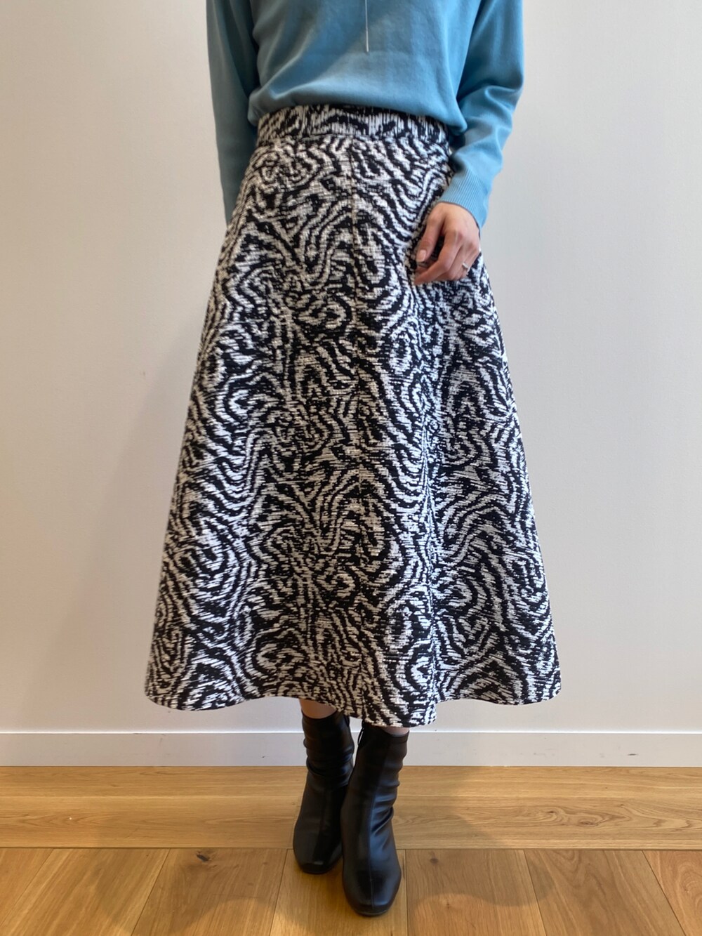 ブルー系のニット/セーター、ブラック系のスカート、ブラック系のブーツを着用したレディースの冬コーディネートの4枚目の写真