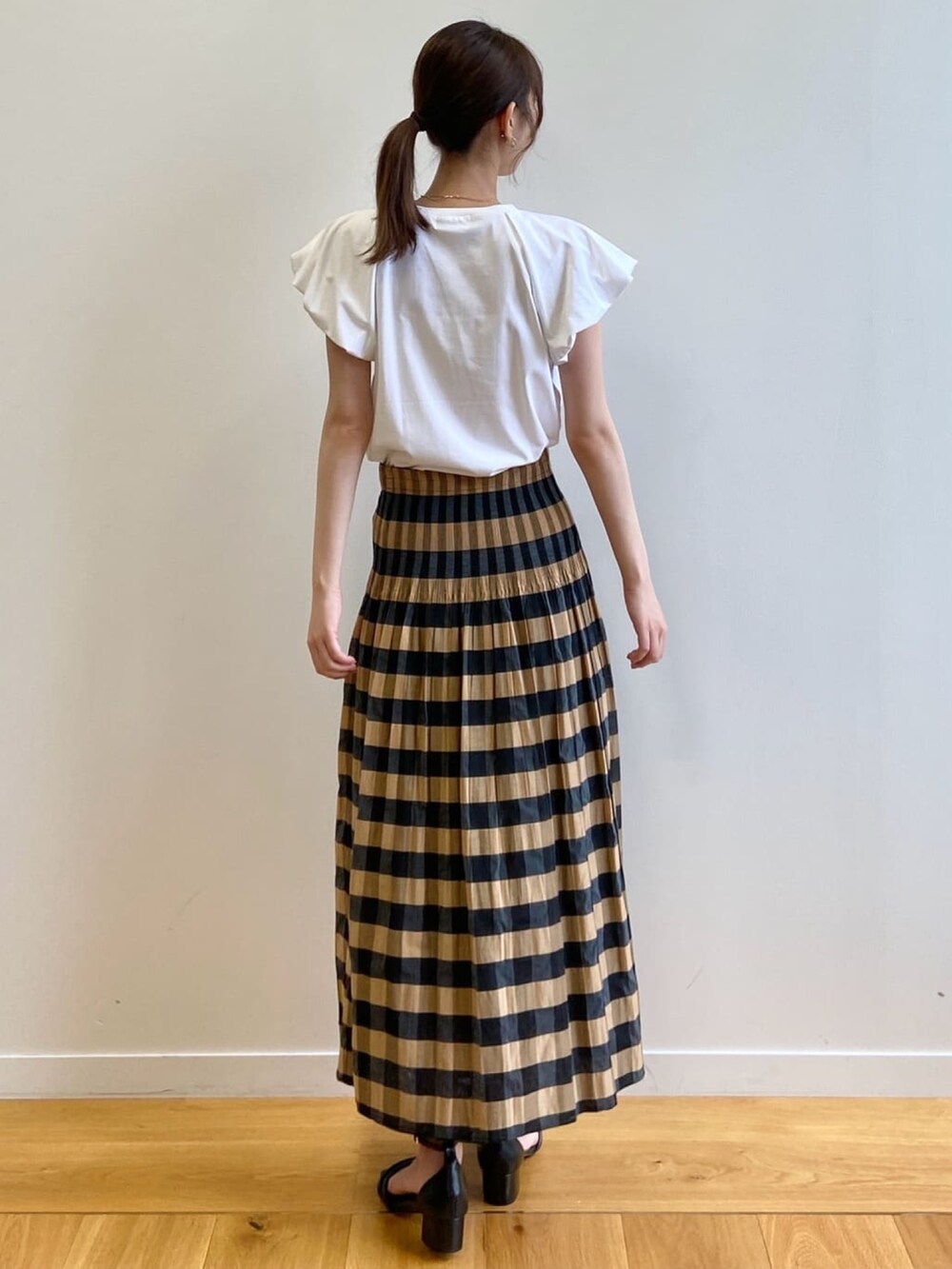 ベージュ系のスカート、ホワイト系のTシャツ/カットソー、ブラック系のサンダルを着用したレディースの夏コーディネートの4枚目の写真