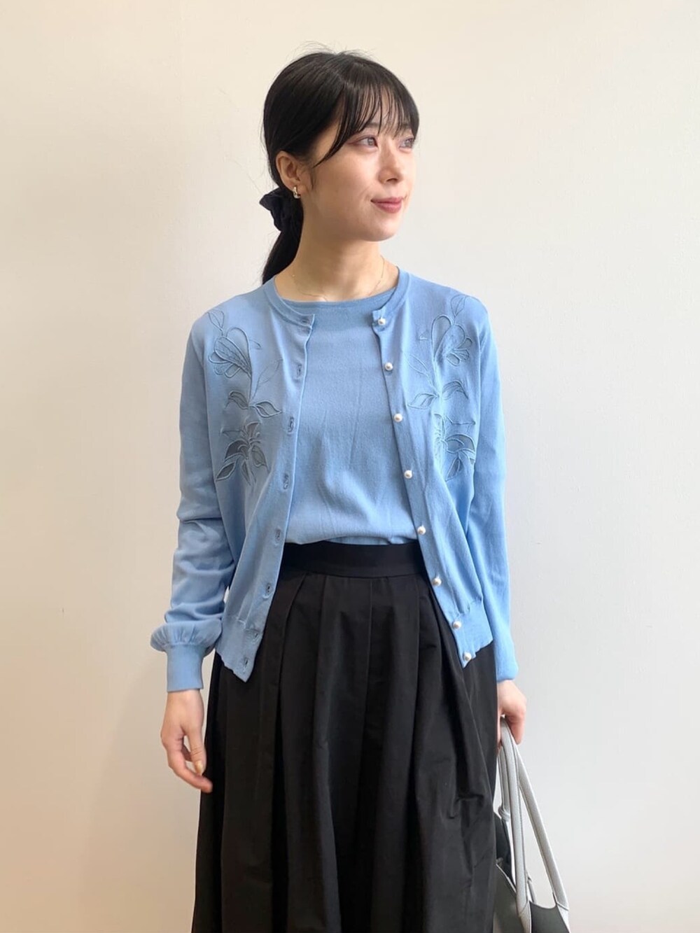 ブルー系のカーディガン/ボレロ、ブルー系のニット/セーター、ブラック系のスカートを着用したレディースの春コーディネートの3枚目の写真