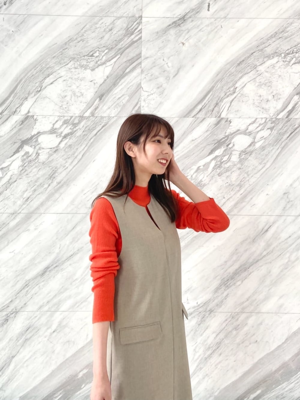 オレンジ系のニット/セーター、ベージュ系のワンピース、ホワイト系のブーツを着用したレディースの秋コーディネートの5枚目の写真