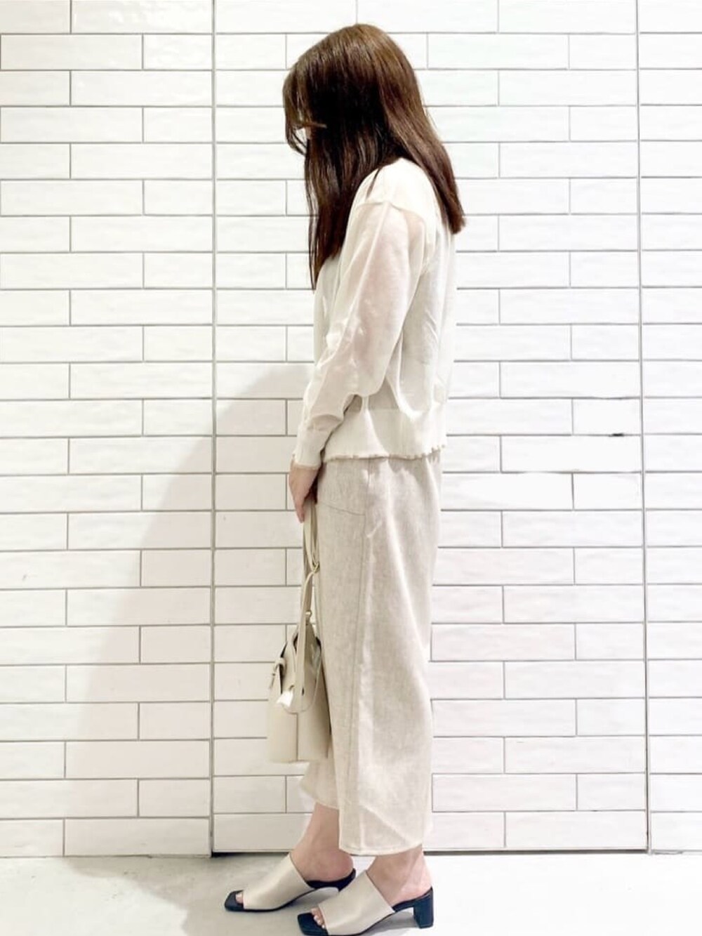 ホワイト系のカーディガン/ボレロ、ベージュ系のニット/セーター、ホワイト系のサンダルを着用したレディースの夏コーディネートの2枚目の写真