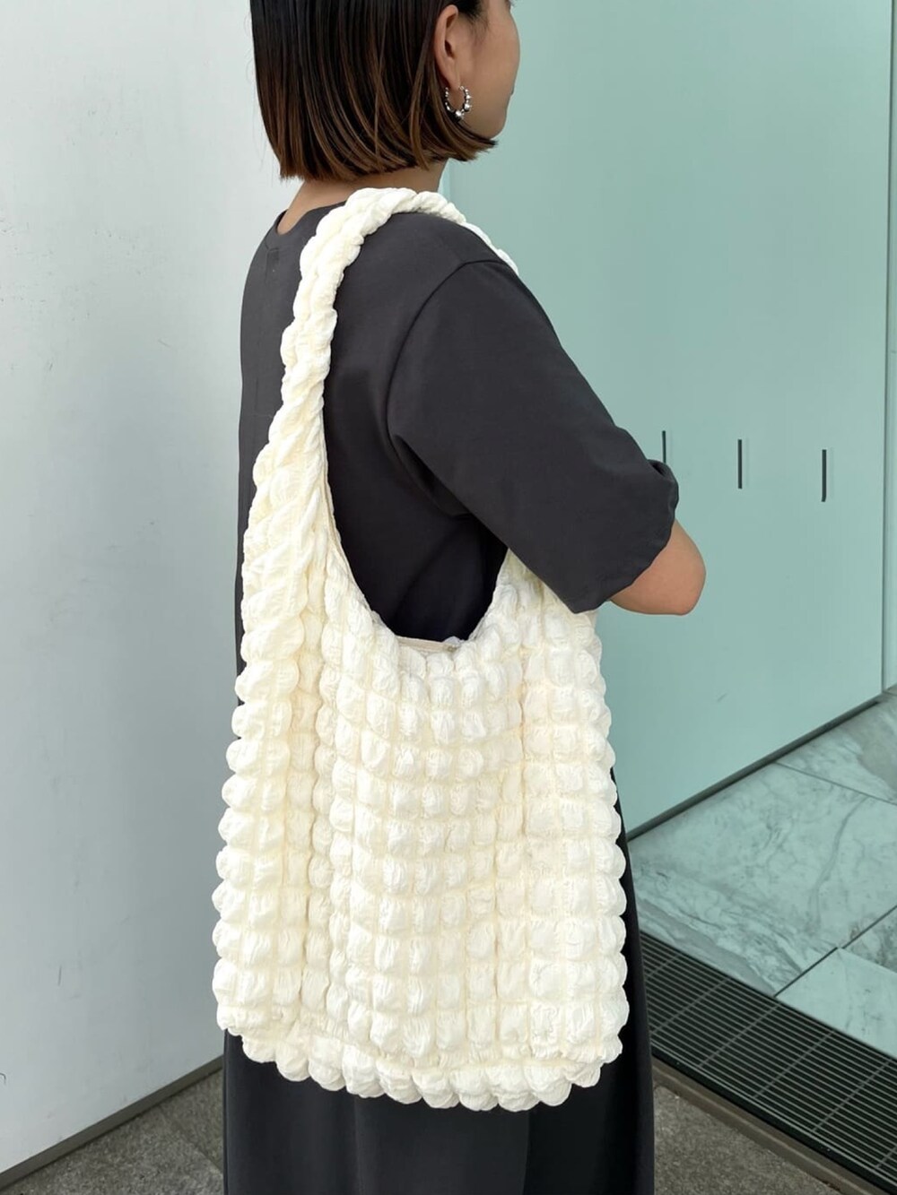 グレー系のワンピース、ホワイト系のサンダル、ホワイト系のショルダーバッグを着用したレディースの春コーディネートの5枚目の写真