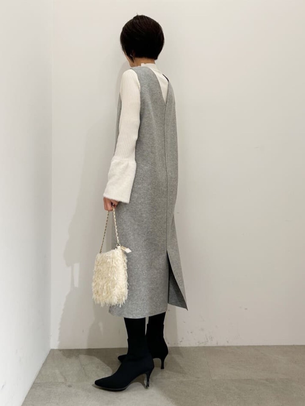 グレー系のスカート、ホワイト系のニット/セーター、ホワイト系のショルダーバッグを着用したレディースの冬コーディネートの2枚目の写真