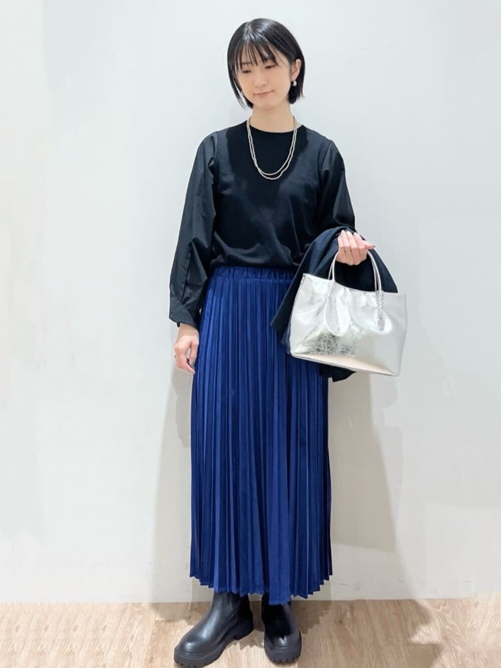 ブルー系のスカート、ブルー系のテーラードジャケット、ブラック系のニット/セーターを着用したレディースの秋コーディネートの2枚目の写真