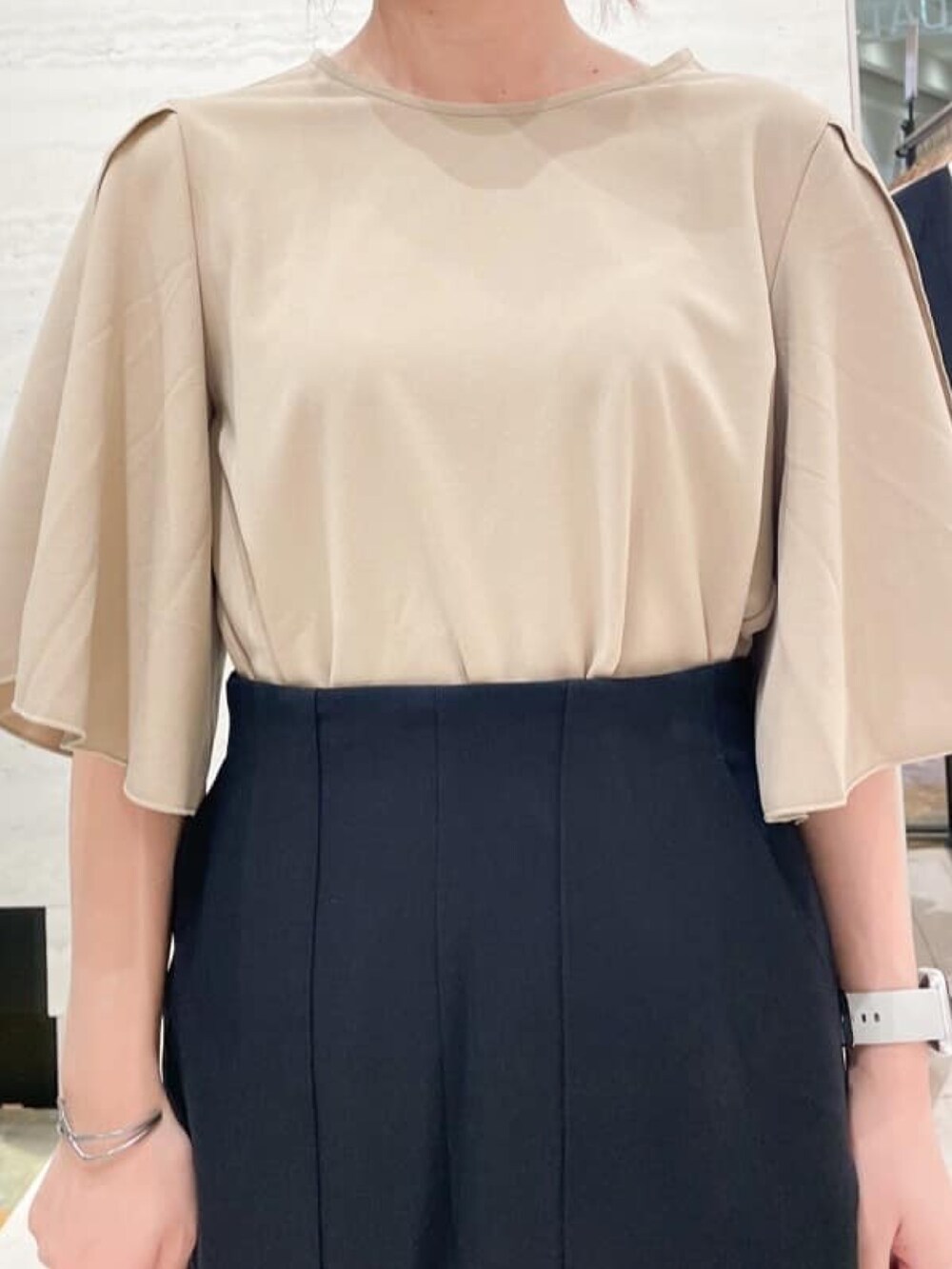 ベージュ系のTシャツ/カットソー、ブラック系のスカート、ブラック系のパンプスを着用したレディースの秋コーディネートの2枚目の写真