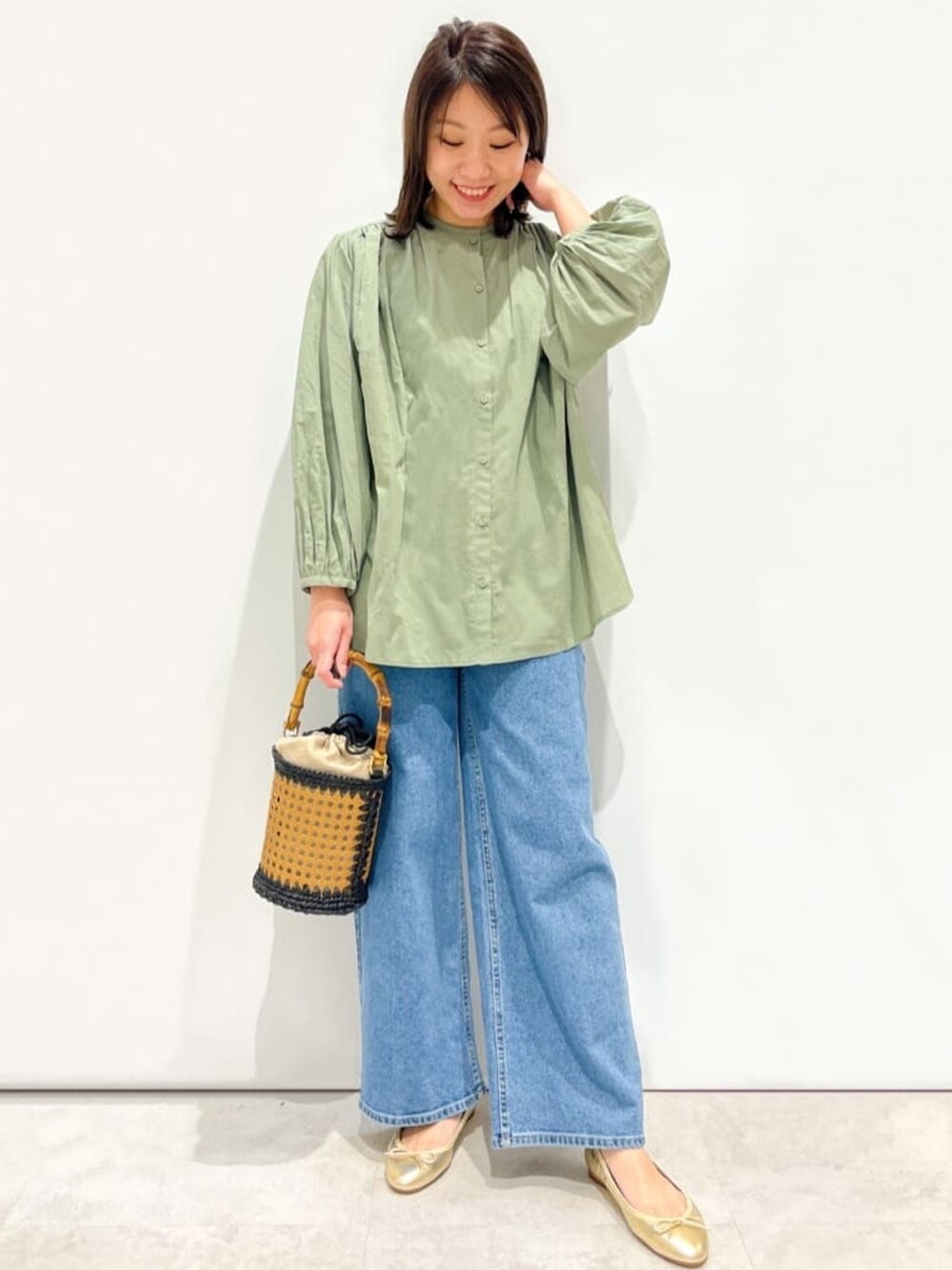 グリーン系のシャツ/ブラウス、ゴールド系のパンプス、ブラック系のトートバッグを着用したレディースの春コーディネートの4枚目の写真