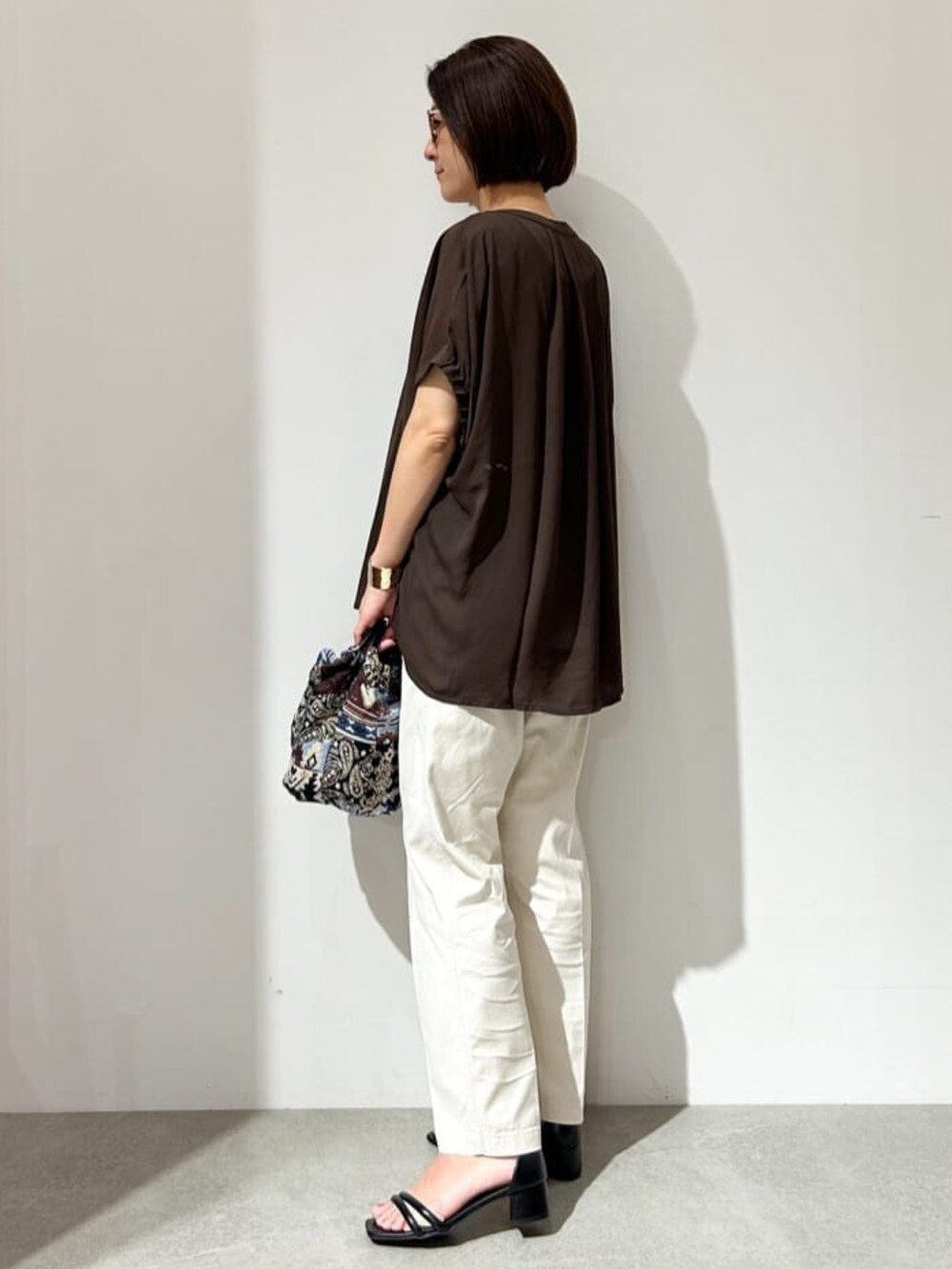 ブラウン系のTシャツ/カットソー、ブルー系のハンドバッグ、ブラック系のサンダルを着用したレディースの夏コーディネートの3枚目の写真