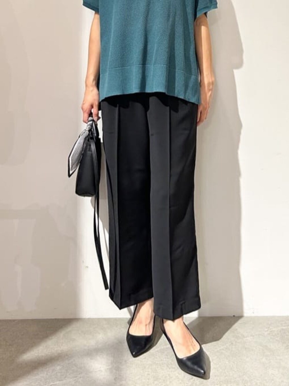 グリーン系のニット/セーター、ブラック系のパンプス、ブラック系のその他パンツを着用したレディースの夏コーディネートの2枚目の写真