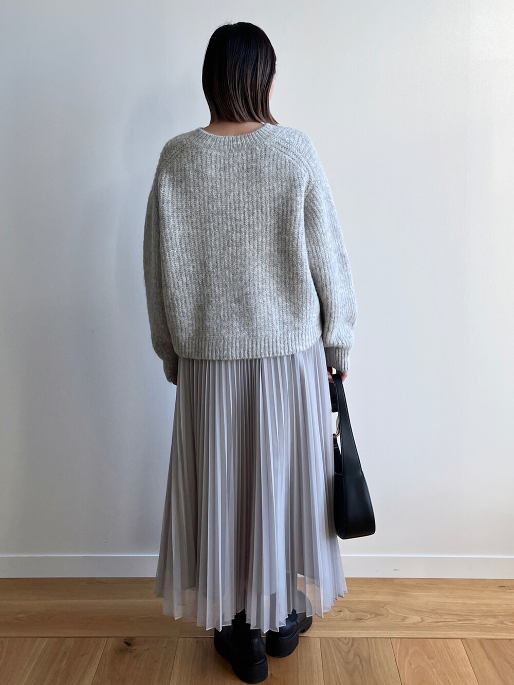 グレー系のニット/セーター、グレー系のスカート、ブラック系のブーツを着用したレディースの冬コーディネートの3枚目の写真