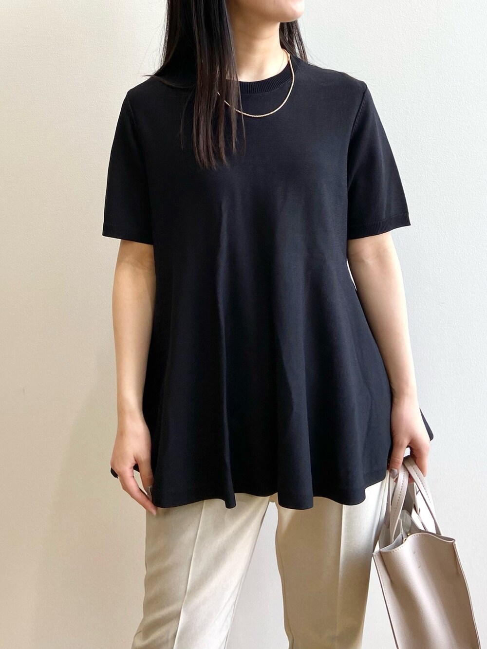 ブラック系のニット/セーター、ベージュ系のその他パンツ、ベージュ系のトートバッグを着用したレディースの春コーディネートの4枚目の写真