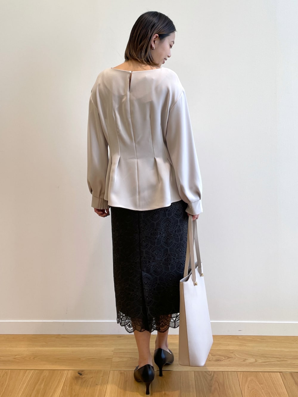 グレー系のシャツ/ブラウス、グレー系のスカート、ベージュ系のトートバッグを着用したレディースの冬コーディネートの3枚目の写真