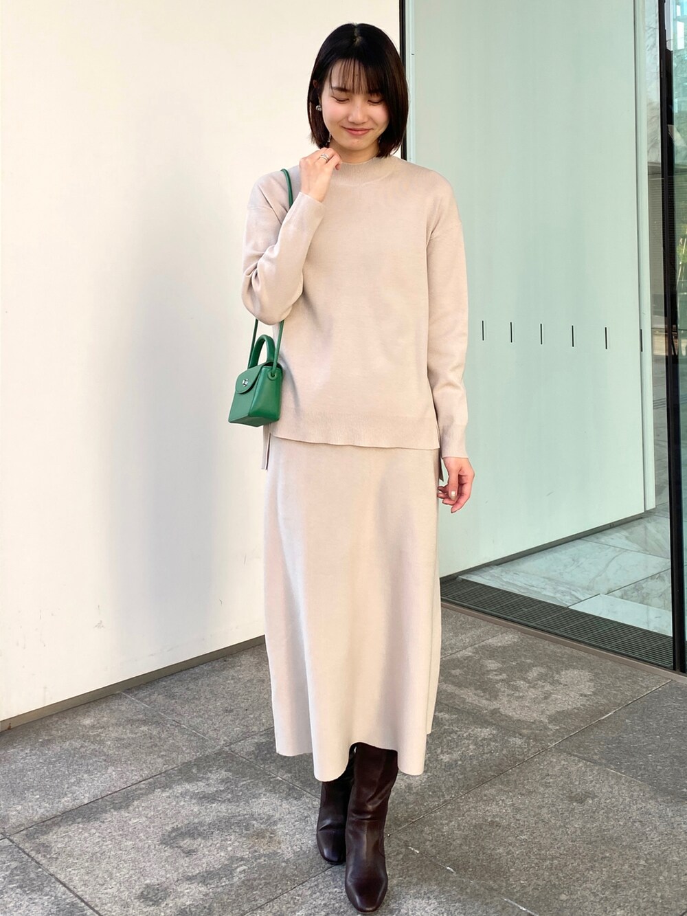 ホワイト系のブルゾン、ベージュ系のニット/セーター、グリーン系のショルダーバッグを着用したレディースの冬コーディネートの3枚目の写真