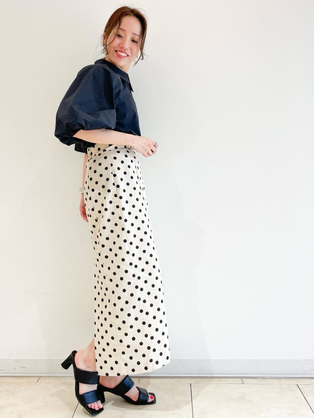 ブラック系のシャツ/ブラウス、ホワイト系のスカート、レッド系のショルダーバッグを着用したレディースの春コーディネートの2枚目の写真