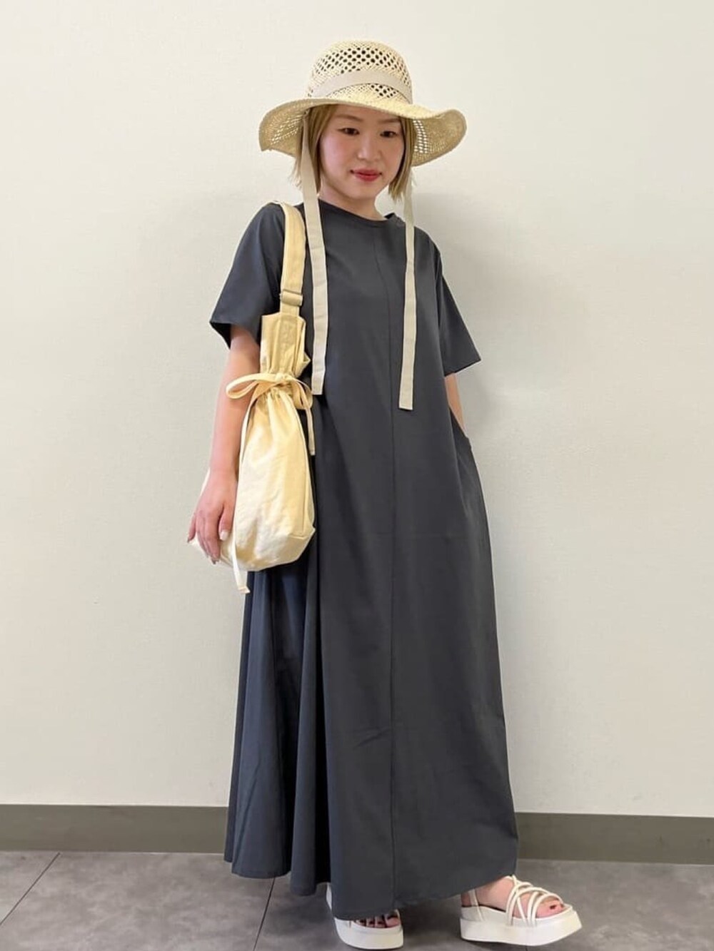 イエロー系のショルダーバッグ、グレー系のワンピース、グレー系のサンダルを着用したレディースの春コーディネートの2枚目の写真