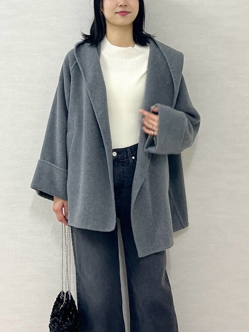 ホワイト系のニット/セーター、グレー系のその他アウター、ブラック系のショルダーバッグを着用したレディースの冬コーディネートの7枚目の写真